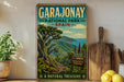 A vintage-style poster of Garajonay National Park in Spain, featuring a lush tropical landscape with a mountain backdrop and a sign indicating the "La Gomera Reserve Biosphere".