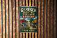 A vintage metal sign for the Geneseo Country Village & Museum, featuring an illustration of a small town with a watermill and a horse-drawn carriage.