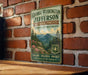 A vintage-style metal sign with text and a mountain landscape illustration is mounted on a brick wall.