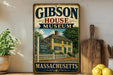 A vintage-style metal sign for the Gibson House Museum in Massachusetts, featuring an illustration of a yellow house with a white picket fence.