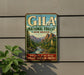 A vintage-style metal sign for the Gila National Forest in New Mexico, featuring a scenic mountain landscape with a river and desert vegetation.
