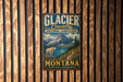 A vintage metal sign for Glacier Country Cultural Landscape, featuring a mountain landscape with a white goat, mounted on a wooden wall.