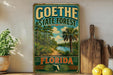 A vintage-style sign for Goethe State Forest in Florida, featuring a tropical landscape with palm trees and a river.