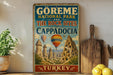 A vintage-style sign advertising the Görme National Park and the rock sites of Cappadocia, Turkey, with a colorful illustration of the rock formations and hot air balloons.