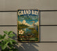 A vintage-style sign for the Grand Bay National Estuarine Research Reserve in Mississippi, featuring a bird, flowers, and a river.