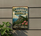 A vintage-style sign for Grandfather Mountain State Park in North Carolina, featuring a mountain landscape with pink flowers.