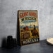 A vintage-style metal sign for Grant-Kohrs Ranch, featuring a cowboy on horseback and a scenic landscape, is displayed on a gray countertop.