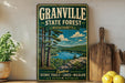 A vintage-style metal sign for Granville State Forest in Massachusetts, featuring a scenic landscape with pine trees, a lake, and mountains.
