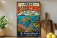 A vintage-style metal sign with the text "GREAT BARRIER REEF AUSTRALIA" and an illustration of a sea turtle swimming among colorful coral and fish.