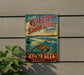 A vintage-style metal sign advertising the Great Sandy Strait in Australia, featuring a scenic image of the strait and a turtle swimming in the water.