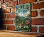 A vintage-style metal sign for the Green Ridge State Forest in Maryland, featuring a scenic landscape with mountains, pine trees, and pink flowers.