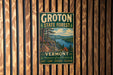 A vintage metal sign for Groton State Forest in Vermont, featuring a scenic landscape with mountains, trees, and a lake.