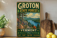 A vintage-style sign for Groton State Forest in Vermont, featuring a scenic landscape with a river and mountains.