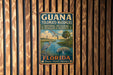A vintage metal sign for the National Estuarine Research Reserve in Florida, featuring a bird and palm trees, mounted on a wooden wall.