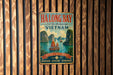 A vintage metal sign with a tropical island scene and a boat, hanging on a wooden wall.