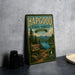 A vintage-style metal sign for the Hapgood State Forest in Vermont, featuring a scenic landscape with pine trees, a lake, and mountains.