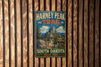 A vintage metal sign for the Harney Peak Trail in South Dakota, featuring a mountain landscape and trail information.