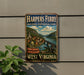 A vintage-style metal sign for the Harpers Ferry National Historical Park in West Virginia, featuring a scenic image of the park and a bridge.