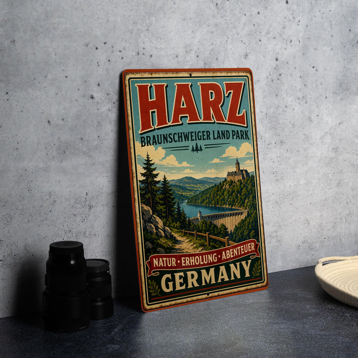A vintage metal sign for Harz, Braunswiger Land Park, featuring a scenic landscape with a castle, trees, and a river.