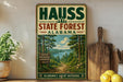 a vintage-style metal sign for the Haus State Forest in Alabama, with a scenic illustration of a forest and a lake. The sign is displayed on a wooden shelf, surrounded by various kitchen utensils and a potted plant.