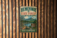 A vintage metal sign for Hemenway State Forest in New Hampshire, featuring a scenic landscape with a river, mountains, and pine trees.