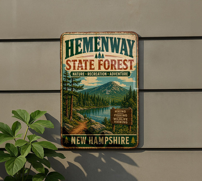 A vintage-style metal sign for Hemenway State Forest in New Hampshire, featuring a scenic landscape with a mountain, river, and pine trees.