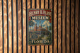 A vintage-style metal sign for the Henry B. Plant Museum in Florida, featuring an illustration of a historic building surrounded by palm trees.