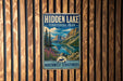 A vintage-style sign for "Hidden Lake" in the Northwest Territories, featuring a scenic landscape with mountains, a lake, and a moose.