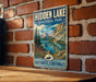 A vintage-style metal sign for Hidden Lake Territorial Park, featuring a scenic mountain landscape with a lake and pine trees.