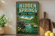 a vintage-style sign for Hidden Springs State Forest in Illinois, with a scenic illustration of a forest and a river. The sign is displayed on a wooden shelf, surrounded by various kitchen utensils and a potted plant.