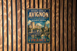 A vintage metal sign for the Avignon Bridge in France, featuring an illustration of the bridge and surrounding architecture.