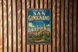 A vintage-style metal sign with the text "HISTORIC CENTRE OF SAN GIMIGNANO ITALY" and an illustration of a cityscape, hanging on a wooden wall.