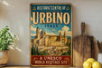 A vintage-style metal sign for the Historic Centre of Urbino, Italy, featuring an illustration of the historic city of Urbino.