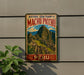 A vintage-style metal sign with the text "Historic Sanctuary of Machu Picchu" and "Peru" is displayed on a wall, with a plant to the left.