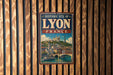 A vintage-style metal sign with the text "HISTORIC SITE OF LYON FRANCE" and an illustration of a cityscape with a river and a bridge.
