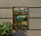 A vintage metal sign for the Holmes State Forest in North Carolina, featuring a scenic image of a forest and a river.