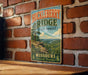 A vintage-style metal sign for Huckleberry Ridge State Forest in Missouri, featuring a scenic landscape with a mountain and a river.