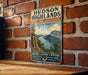 A vintage-style metal sign for Hudson Highlands, New York, featuring a scenic landscape with mountains, a lake, and a sailboat.