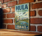 A vintage-style metal sign with the text "HULA NATURE RESERVE ISRAEL" is displayed on a brick wall.