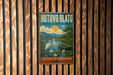 A vintage-style metal sign with a scenic illustration of a lake, boat, and birds, mounted on a wooden wall.