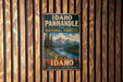 A vintage-style metal sign for Idaho Panhandle National Forests, featuring a scenic landscape with mountains, pine trees, and a lake.
