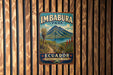 A vintage metal sign for Imbabura Park in Ecuador, featuring a mountain landscape and a trail leading to a lake.