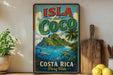A vintage-style sign for "Isla del Coco" in Costa Rica, featuring a tropical island landscape with palm trees, a blue ocean, and various marine life.