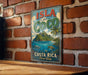 A vintage-style sign for the island of Costa Rica, featuring a tropical landscape with palm trees, a blue ocean, and a mountain range.
