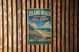 A vintage metal sign for Island Beach State Park in New Jersey, featuring a beach scene and the text "New Jersey's Longest Barrier Island" and "Beaches - Wild - Adventure".