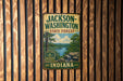 A vintage metal sign for Jackson-Washington State Forest, Indiana, featuring a scenic landscape with a river and trees.
