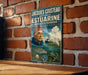A vintage-style poster featuring a man in a fishing hat, surrounded by marine life, is displayed on a brick wall.