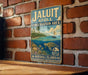 A vintage metal sign for the Jaluit Conservation Area, featuring a tropical beach scene with a sailboat, palm trees, and marine life.