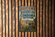 A vintage-style metal sign with the text "JESUIT BLOCK AND ESTANCIAS OF CORDOBA ARGENTINA" displayed on a wooden wall.