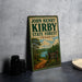 A vintage-style metal sign for John Henry Kirby State Forest in Texas, featuring a scenic illustration of a forest and a lake.